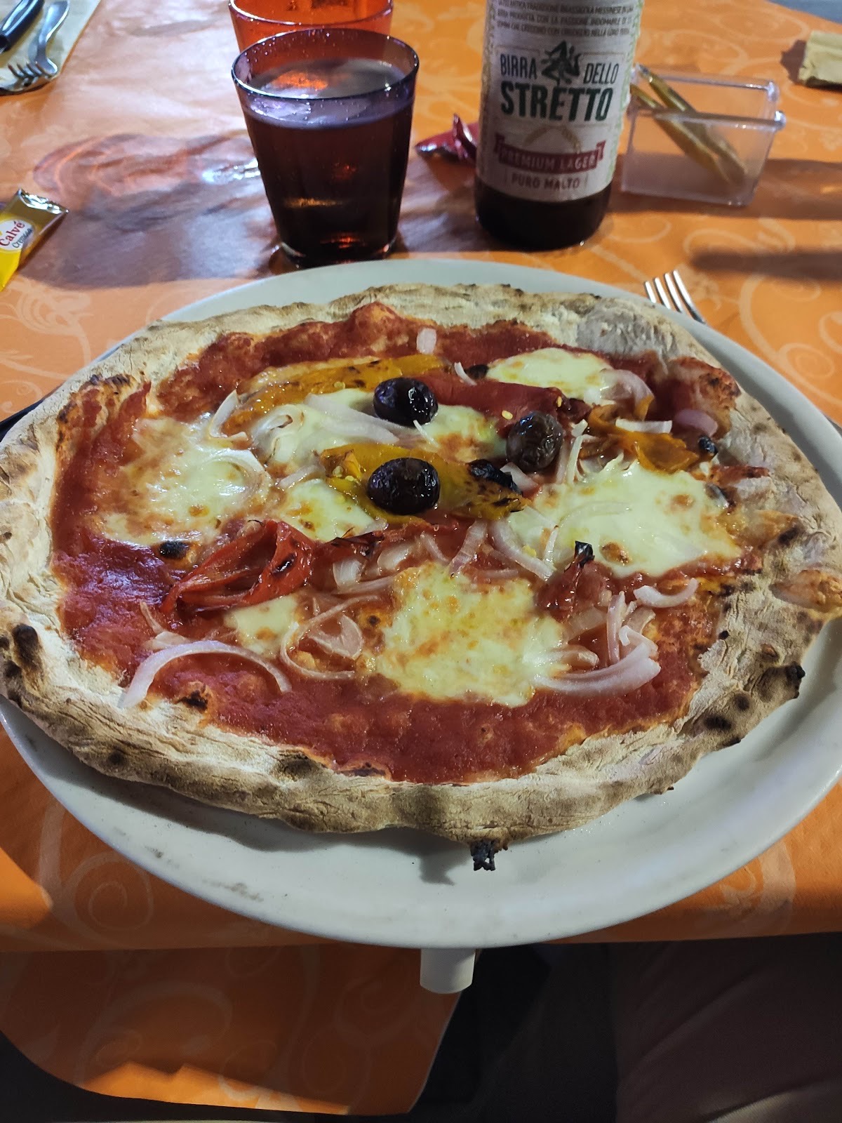 Pizza appena sfornata a La Piazzetta, con peperoni, cipolla e olive